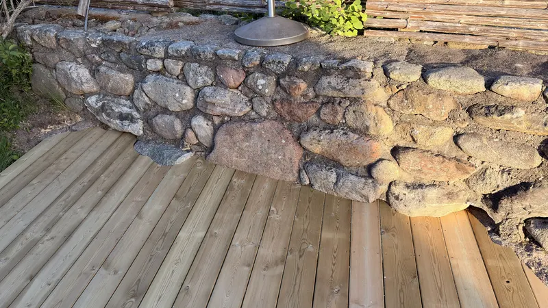 Träaltan monterad intill gammal naturstenmur