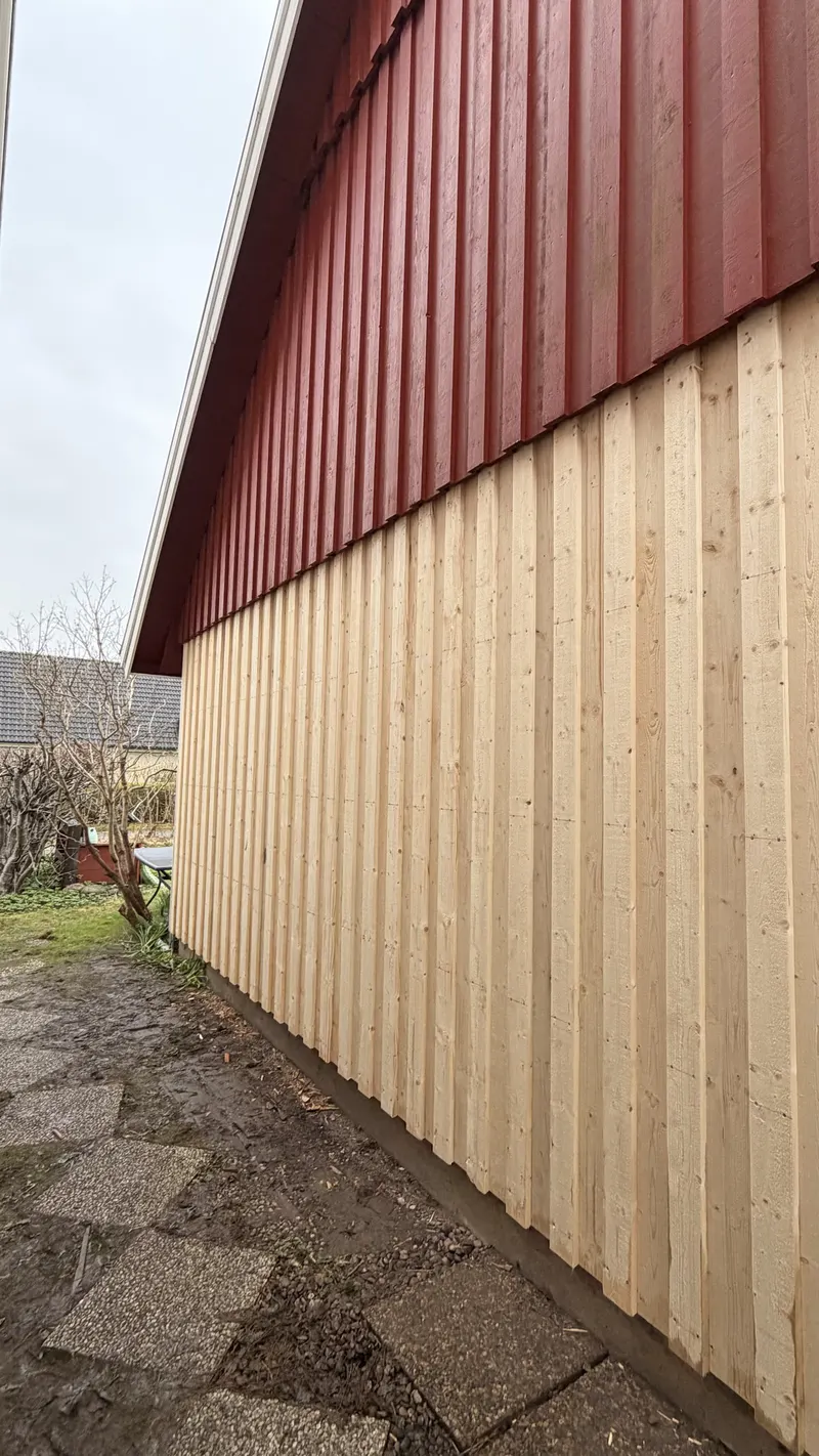 Ny träpanel halvvägs upp på fasad, övre halvan Falurött