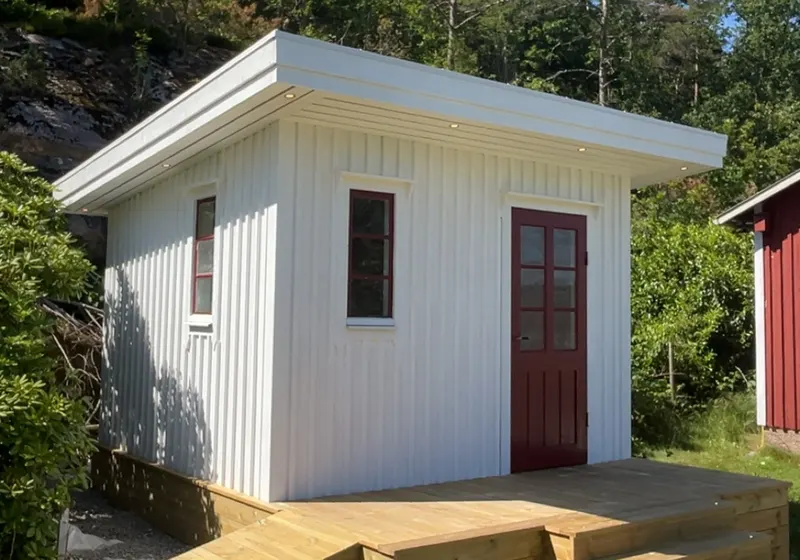 Vit friggebod med altan, trappa och ramp